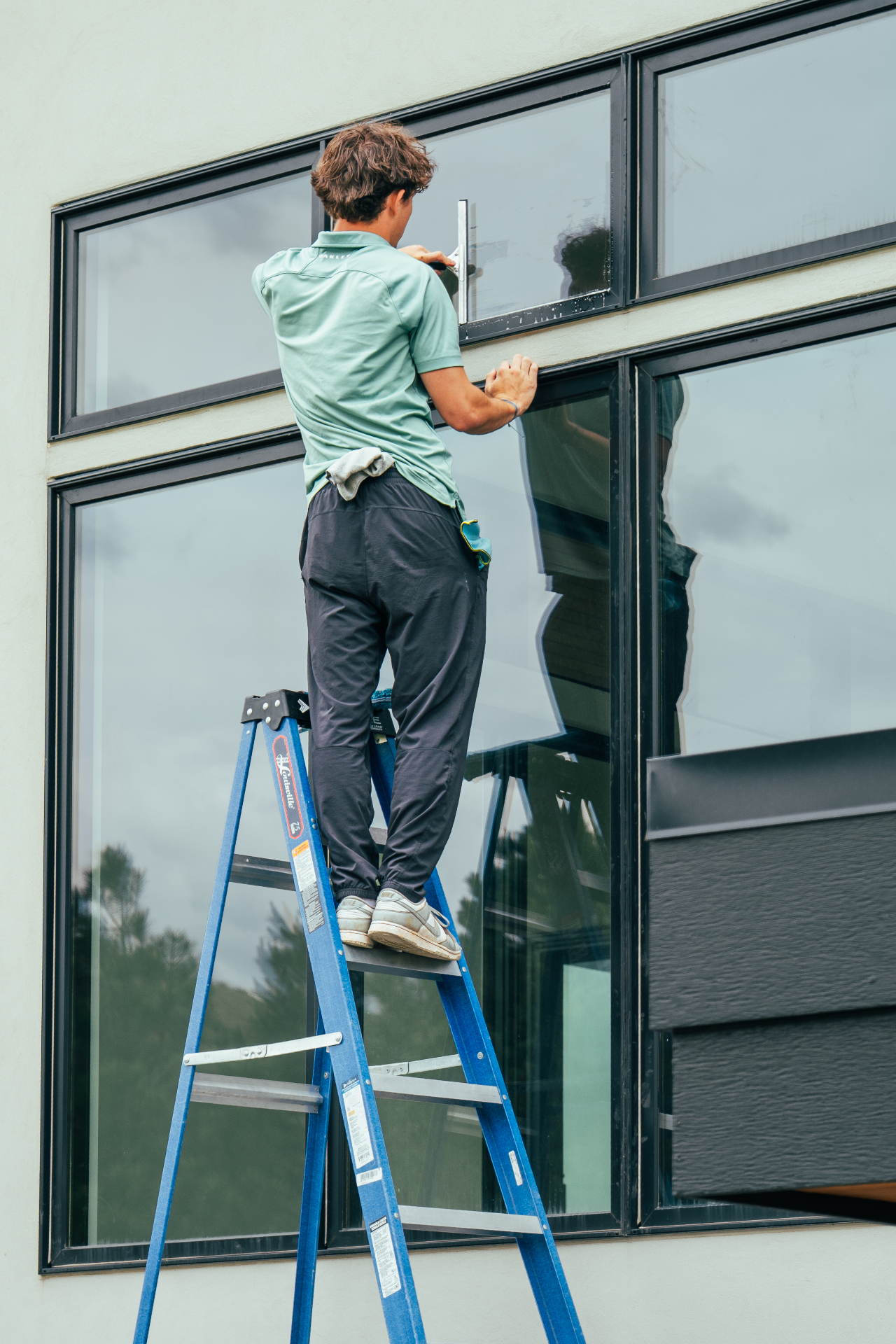 Technician cleaning exterior windows with a squeegee