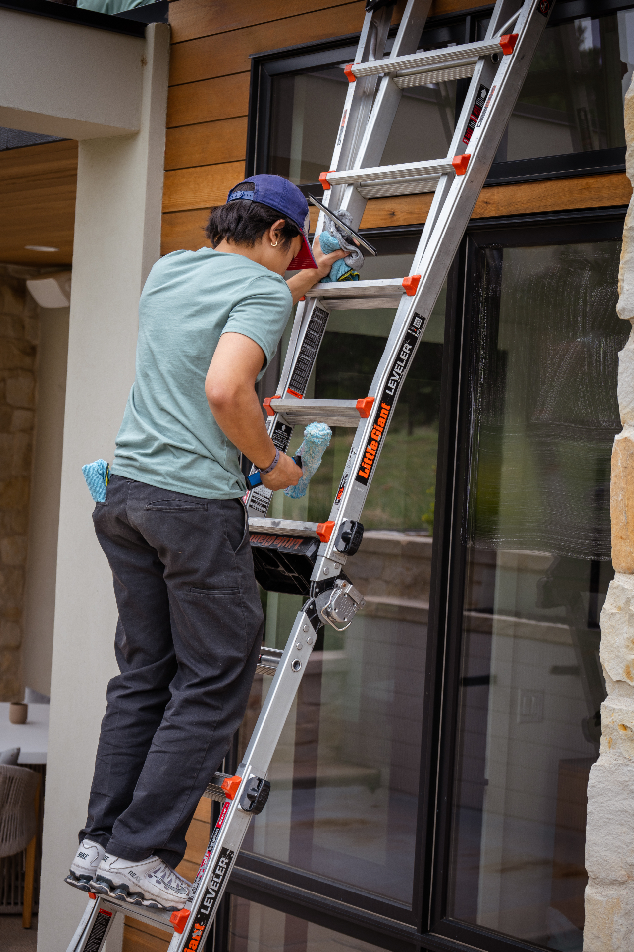Team member squeegeeing a window from a ladder
